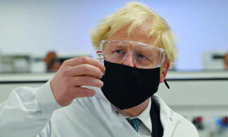 Le Premier ministre Boris Johnson examinant un flacon du vaccin AstraZeneca, à l’usine de fabrication pharmaceutique de Wockhardt à Wrexham, au nord du Pays de Galles.  Ph. AFP